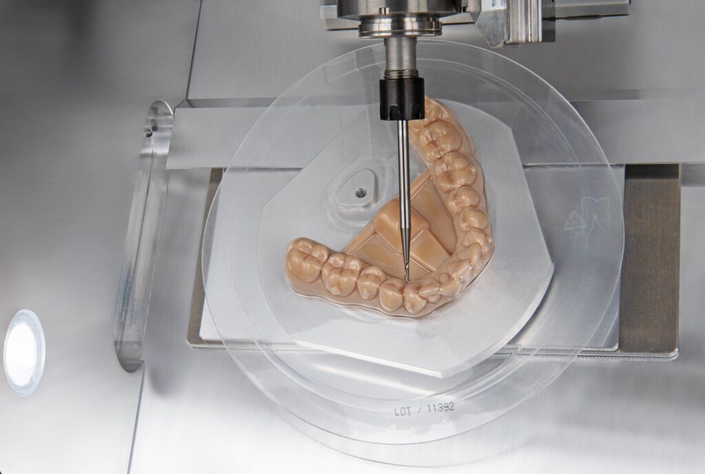 Image shows an dental aligner being trimmed by vhf E3 milling machine