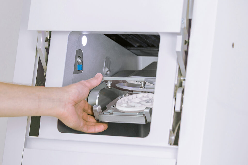 Image shows a technician's hand changing the blanks in a vfh K5+ dental mill