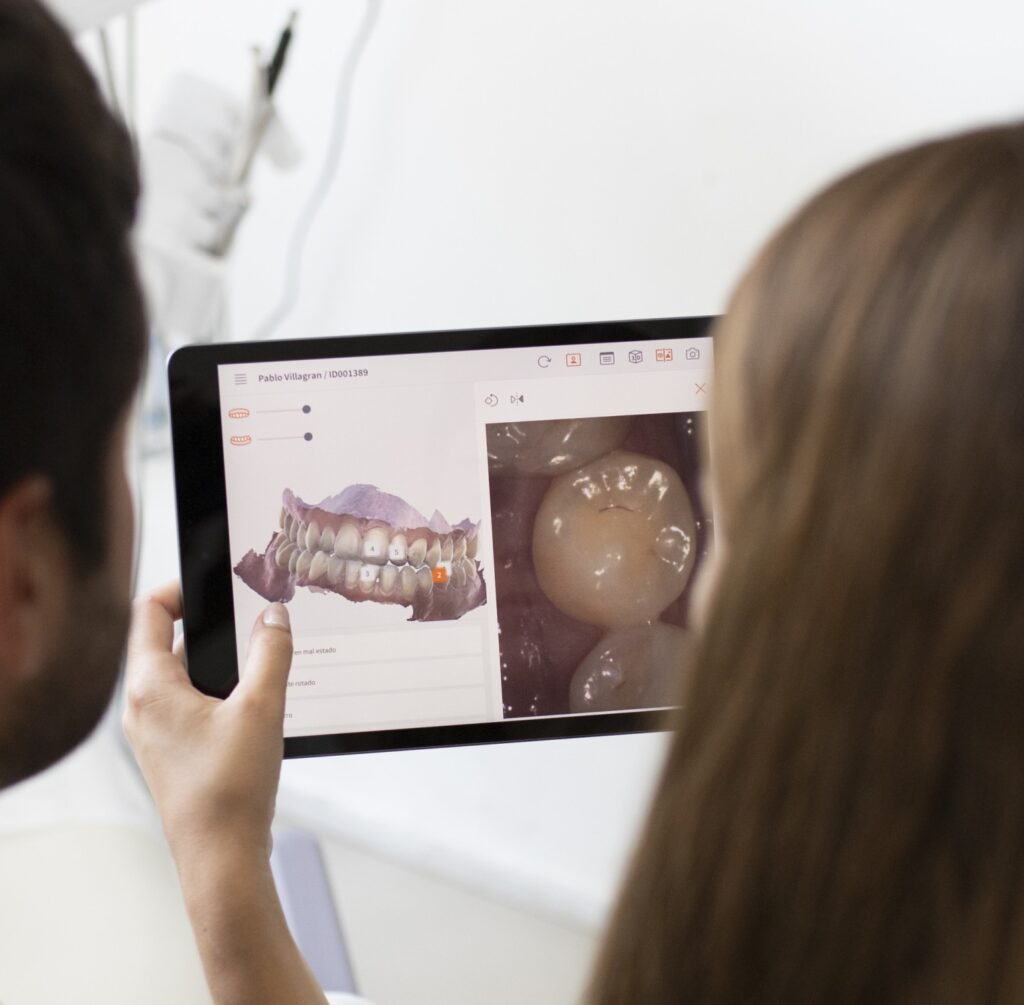 Image of a patient looking at a tablet with an intraoral scanning of the mouth